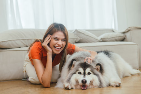 beautiful woman playing with her dog in room at home happilyの写真素材