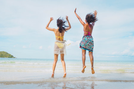Happy beauty woman in bikini jumping together on the beachの写真素材