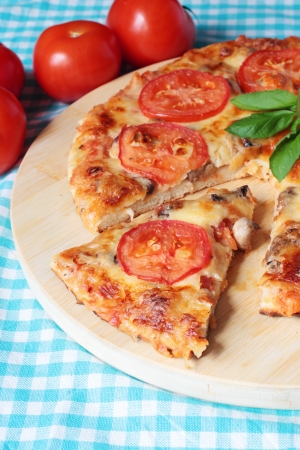 Tasty vegetarian pizza with cheese, tomatoes and mushrooms on a wooden boardの写真素材