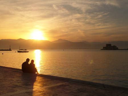 Lovers watching a Romantic Sunset at the Promenade of  Nafplio, Greece