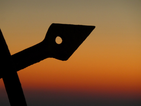 Silhouette of Arrow Shaped Wrought Iron Against the Orange Gradation of Sunset sky, Santorini island of Greece, backgroundの写真素材