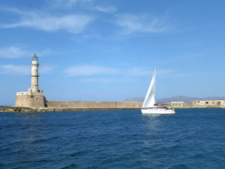 Sailing White Yacht near the Lighthouse on the Blue Aegean Sea, Crete Island, Greeceの写真素材