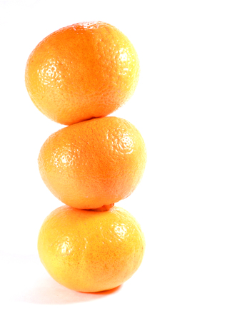Vertically piled up three ripe oranges isolated on white background, close-upの写真素材