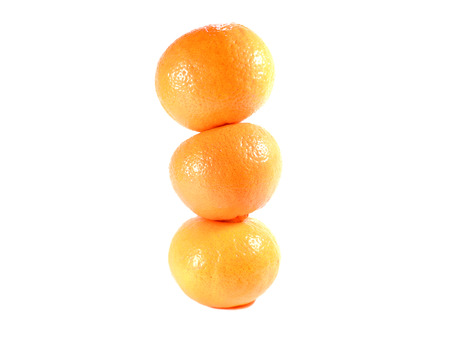 Close-up of vertically piled up three ripe oranges isolated on white backgroundの写真素材