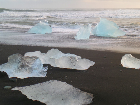 Many of beautiful blue Icebergs on the Black Sand Beach under evening sky, South Iceland