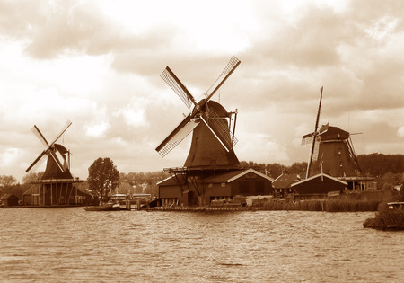 Sepia tone of three waterfront Dutch windmills under the cloudy sky, Zaanse Schans, Netherlandsの写真素材