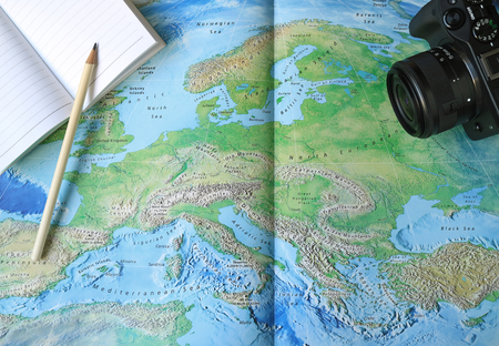 Ready for the Holidays! Lined Note Papers with White Pencil and a Black Camera on the World Mapの写真素材