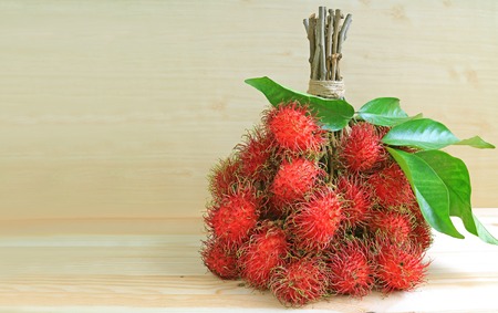 Bunch of Ripe Fresh Rambutan Fruits on Wooden Table, with Free Space for Text and Design