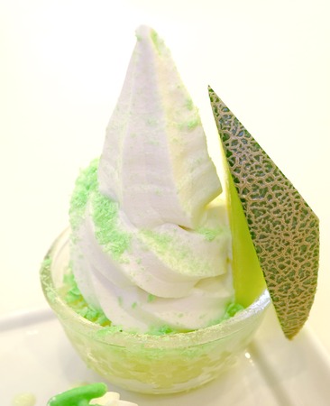 Vanilla Soft Serve Ice Cream with Sliced Cantaloupe Melon Fruit in a Glass Bowl on White Backgroundの写真素材