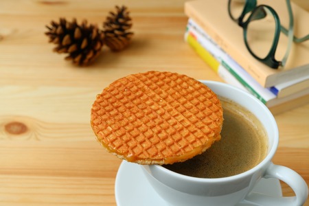 Spending Some Quiet Time with Stroopwafel and a Cup of Hot Coffee served on wooden table, Blurred Backgroundの写真素材