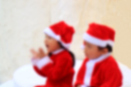Blurred Photo of Little Boy and Girl in Cute Santa Outfits Chilling Out Togetherの写真素材