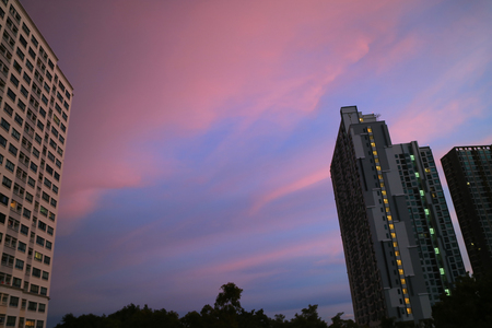 Beautiful pastel pink and blue clouds layer of the sunset sky over the high buildings in Bangkok, Thailandの写真素材