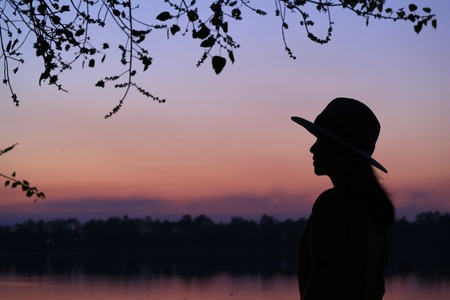 Silhouette of a young woman against beautiful purple color of evening skyの写真素材