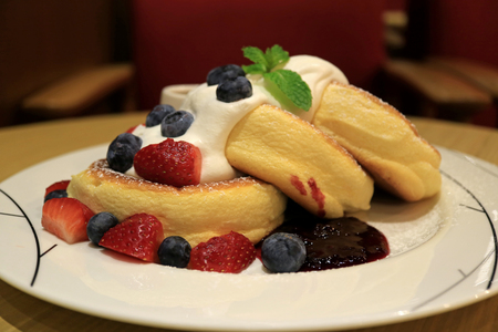 Mouthwatering Fluffy Souffle Pancake with Fresh Whipped Cream and Mix Berries Served on white Plateの写真素材