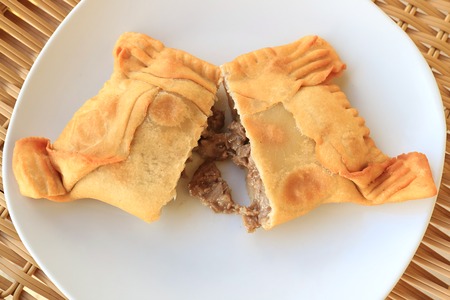 Top view of Empanada de Pino or beef filled Empanada, delicious Chilean baked pasty served on white...