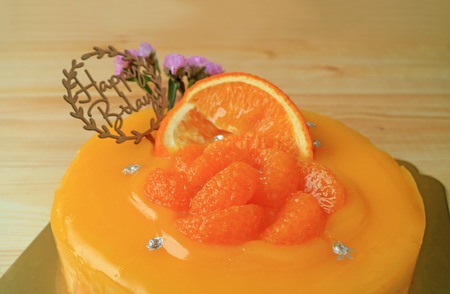 Vibrant Color Mandarin Orange Birthday Cake on the Wooden Tableの写真素材