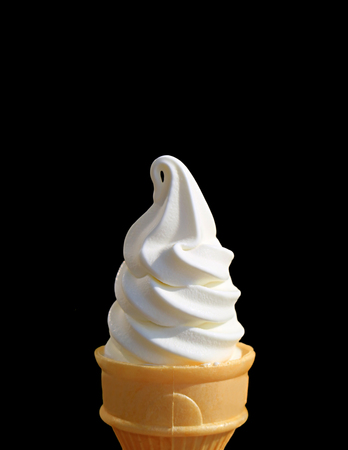Vertical Photo of Pure White Vanilla Soft Serve Ice Cream Cone Isolated on Black Background with Free Space for Text or Designの写真素材