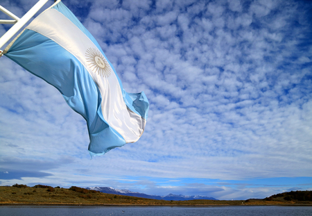 Flag of Argentina of a cruise ship waving in the sunlight against bright cloudy skyの写真素材