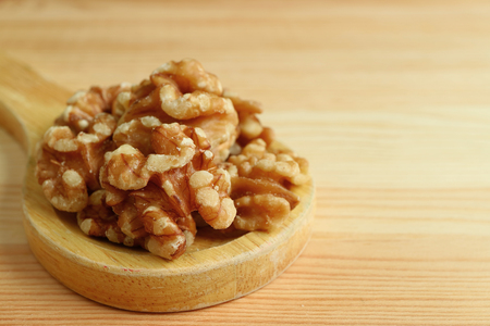 Pile of Walnut Kernels on Wooden Spoon on Wooden Table with Free Space for Text or Designの写真素材