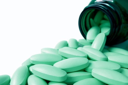 Heap of light mint green color oval shaped pills scattered from glass bottleの写真素材