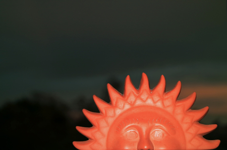 Closed up terracotta sun shaped home decor item against twilight dark blue skyの写真素材