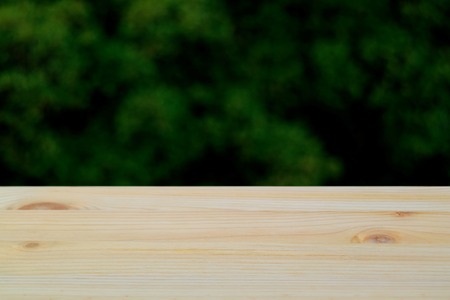 Closed up natural pattern of wooden table top with blurred green tree leaves backgroundの写真素材