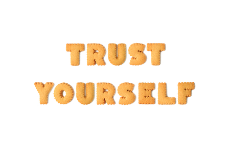 Top view of the word TRUST YOURSELF spelled with alphabet shaped biscuits isolated on white backgroundの写真素材