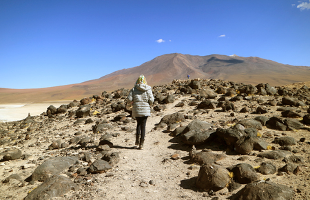 Female traveler walking on the slope of Laguna Verde lake shore, Potosi, Boliviaの写真素材