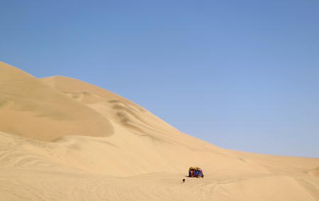 Running dune buggy chasing by a naughty dog on the sand dunes of Huacachina desert, Ica region, Peruの写真素材