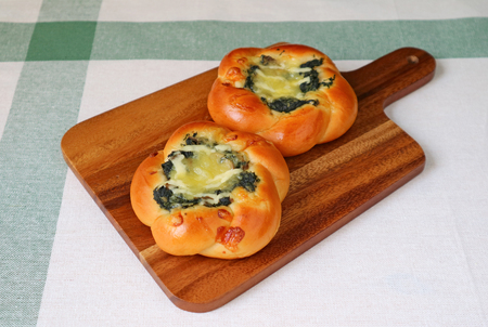 Pair of spinach and cheese buns on a wooden tray