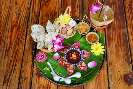 Thai Appetizer Set of Fresh Lotus Petal Wrapped and Crispy Fried Rice Cakes with Calamansi Citrus Juice Served on Wooden Tableの写真素材