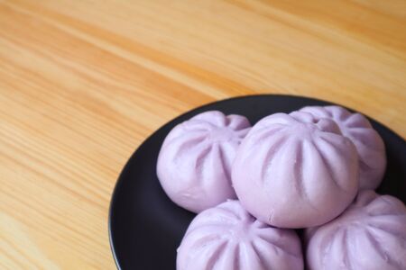 Plate of many purple sweet potato steamed buns on wooden table with copy spaceの写真素材