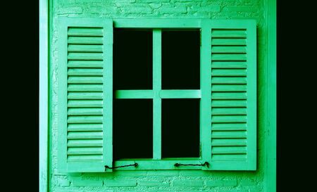 Lime green colored wooden window with shutters on green brick wallの写真素材