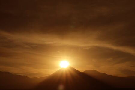 Dazzling Sun Rising on the Peak of Licancabur Volcano as Seen from the Town of San Pedro de Atacama in Northern Chileの写真素材