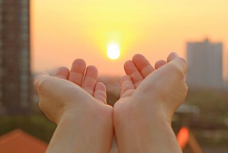 Hands open to the morning sky with the rising sunの写真素材