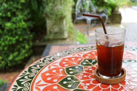 Half Glass of Iced Coffee on Colorful Tiled Table at the Patioの写真素材