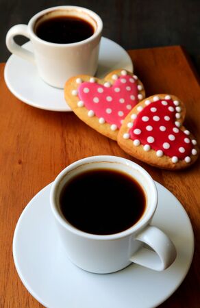 Two cups of coffee and dotted heart shaped royal icing cookies with selective focusの写真素材