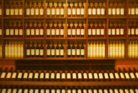 Abstract blurred of wine bottles displayed on wooden shelf for background or wallpaper