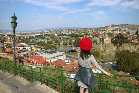 Female Traveler Impressed by the Panoramic Aerial View with Many of Iconic Landmarks of Tbilisi, the Capital City of Georgiaの写真素材
