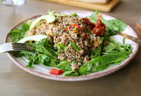 Plate of Quinoa Salad with Arugula and Avocado Served on Wooden Tableの写真素材