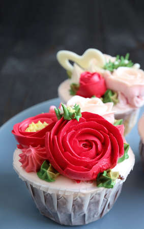 Closeup cupcakes decorated with red flower shaped frosting on pale blue plate