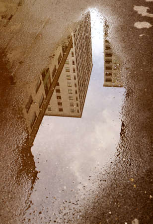 Reflections of high buildings on the puddle in sepia color