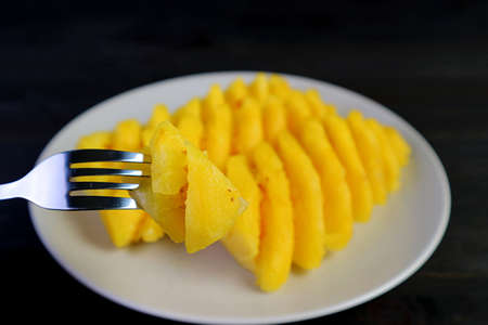 Closeup a chunk of fresh and juicy pineapple with blurry slices of pineapple in the backdropの写真素材