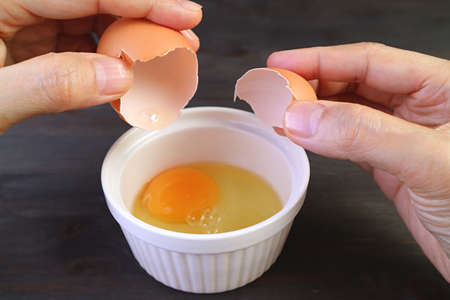 Closeup of man's hand cracking an egg into a bowl