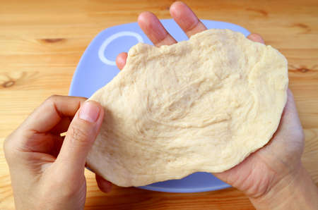 Man's hands stretching the dough for baking homemade bread