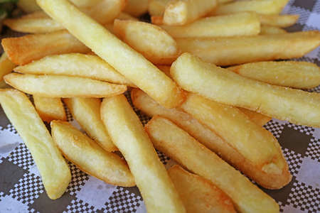 Closeup pile of french fries on checker wax paper