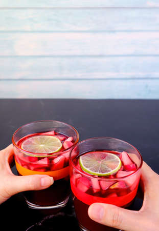 Vertical Image of Man and Woman's Hand Holding Glass of Red Wine Sangria on Black Tableの写真素材