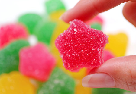 Woman's Hand Picking Vibrant Hot Pink Sugar Coated Fruity Flavored Soft Jelly Candyの写真素材