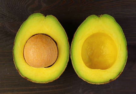 Top view of a cut in half fresh ripe avocado isolated on black wooden background