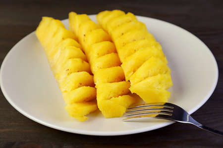 Slices of mouthwatering fresh ripe pineapple in white plateの写真素材